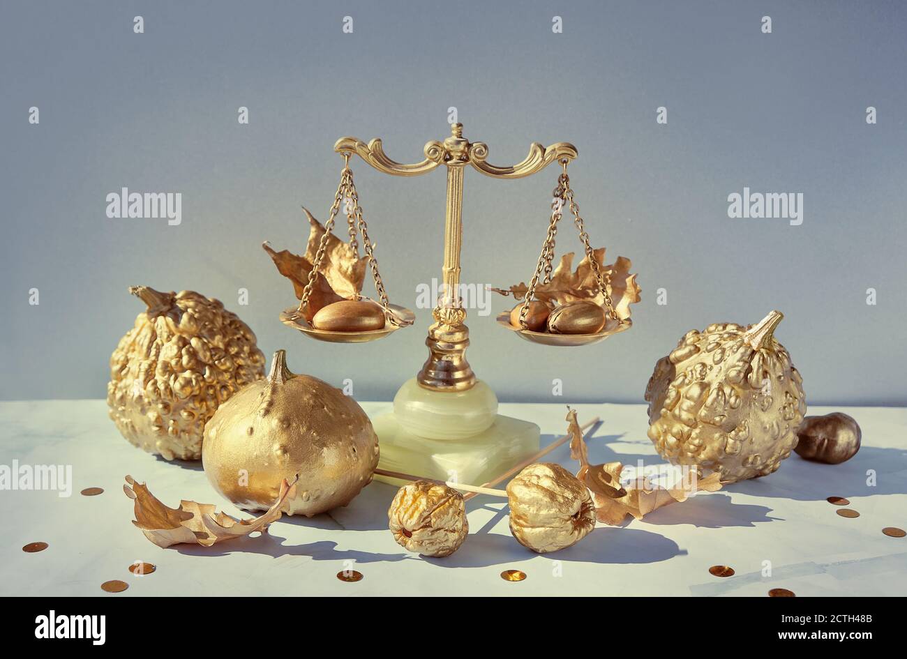 Arrangiamento autunnale in oro e marmo. Bilancia decorativa retrò, zucche d'oro e foglie. Foto Stock