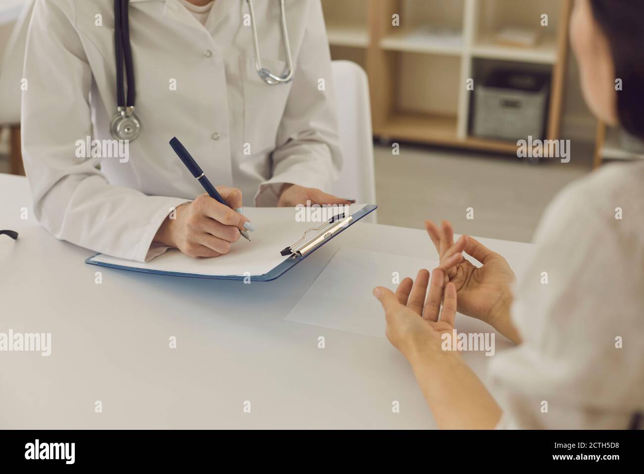 Mani di un medico femminile che scrivono note ad un paziente su un esame medico o su una prescrizione medica. Foto Stock