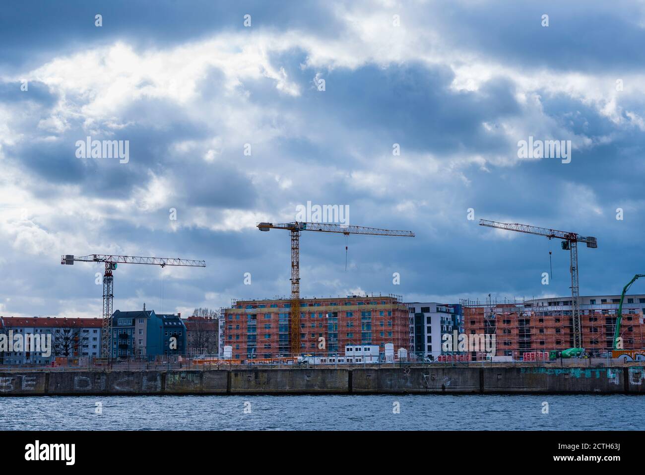 Un cantiere con tre gru, cantiere a Berlino, Germania, tre gru in cantiere, nuvole scure Foto Stock