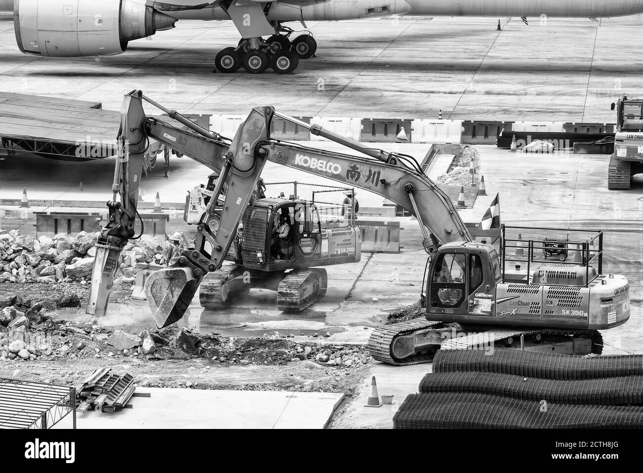 L'immagine in bianco e nero del grembiule dell'aeroporto viene perforata dall'escavatore durante il progresso della ricostruzione. Foto Stock