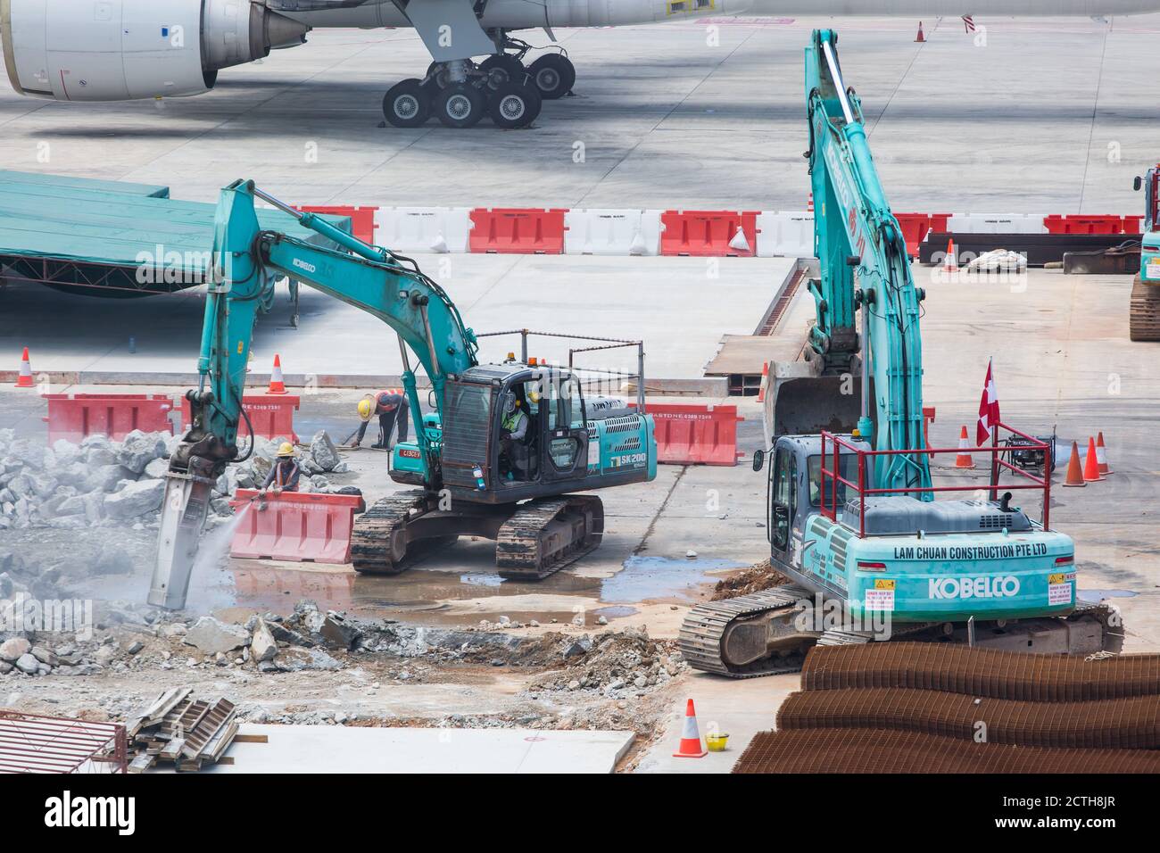 Due escavatori perforano il terreno e scavano su detriti sul grembiule dell'aeroporto Foto Stock