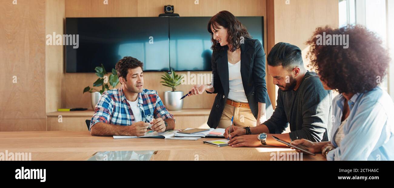 Uomini d'affari multirazziali che si incontrano intorno a un tavolo e discutono nuove strategie. donna d'affari che gestisce un team creativo Foto Stock