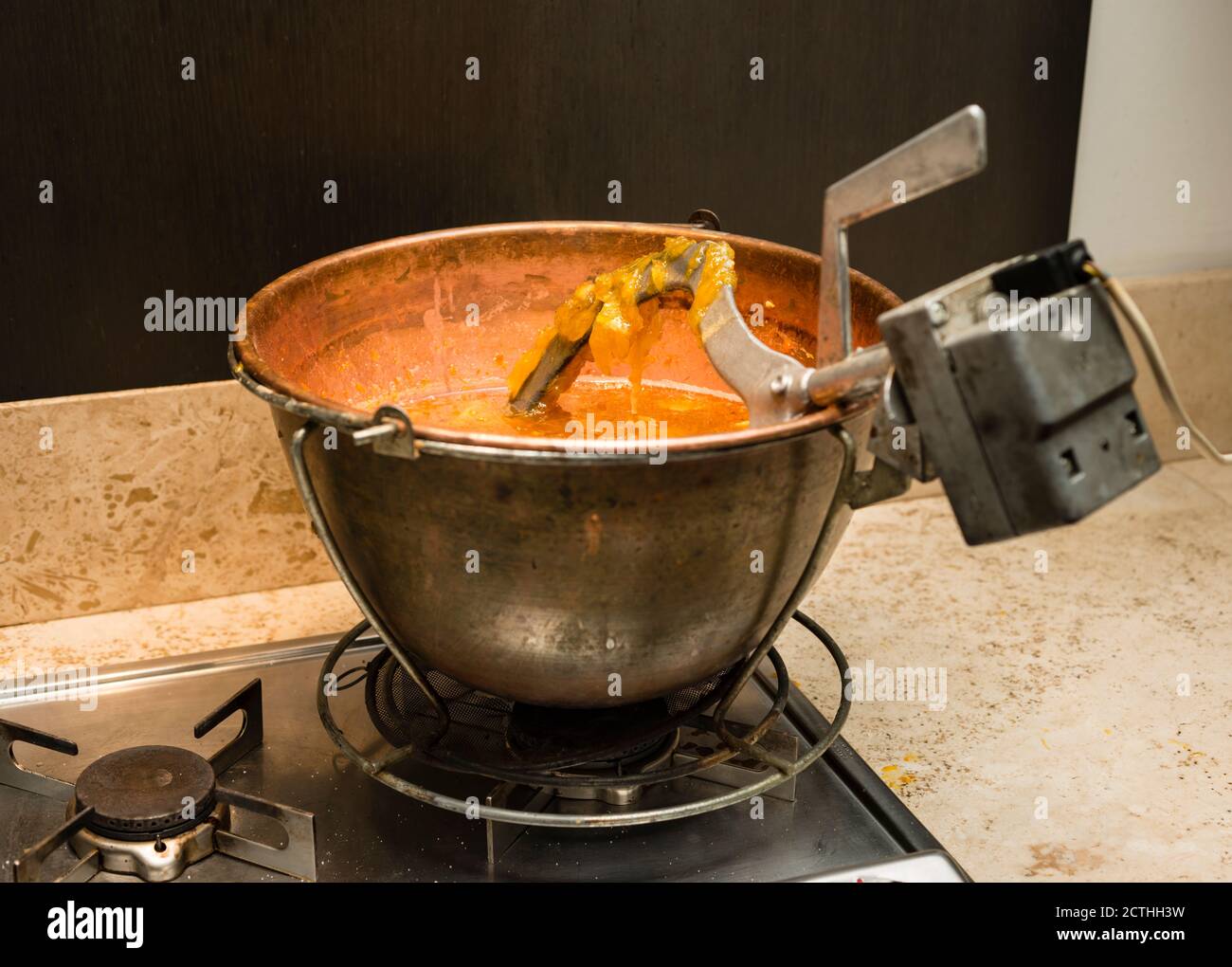 Preparazione di marmellata d'arance casalinga italiana di vecchio stile con braccio di agitazione automatico. Foto Stock