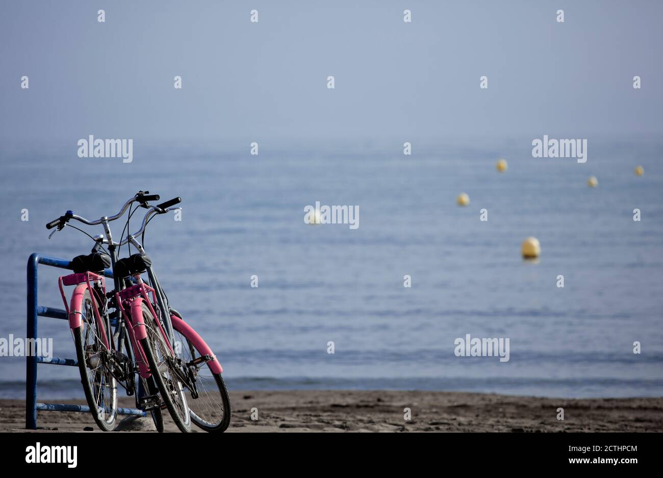 concetto di mobilità ecologica, due classiche biciclette rosa, parcheggiate in riva al mare, Foto Stock