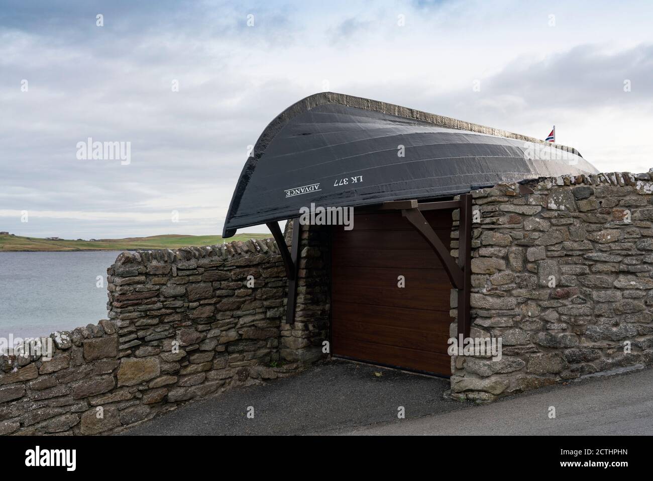 Imbarcazione capovolta che forma il tetto di garage di casa nella città vecchia di Lerwick, Isole Shetland, Scozia, Regno Unito Foto Stock