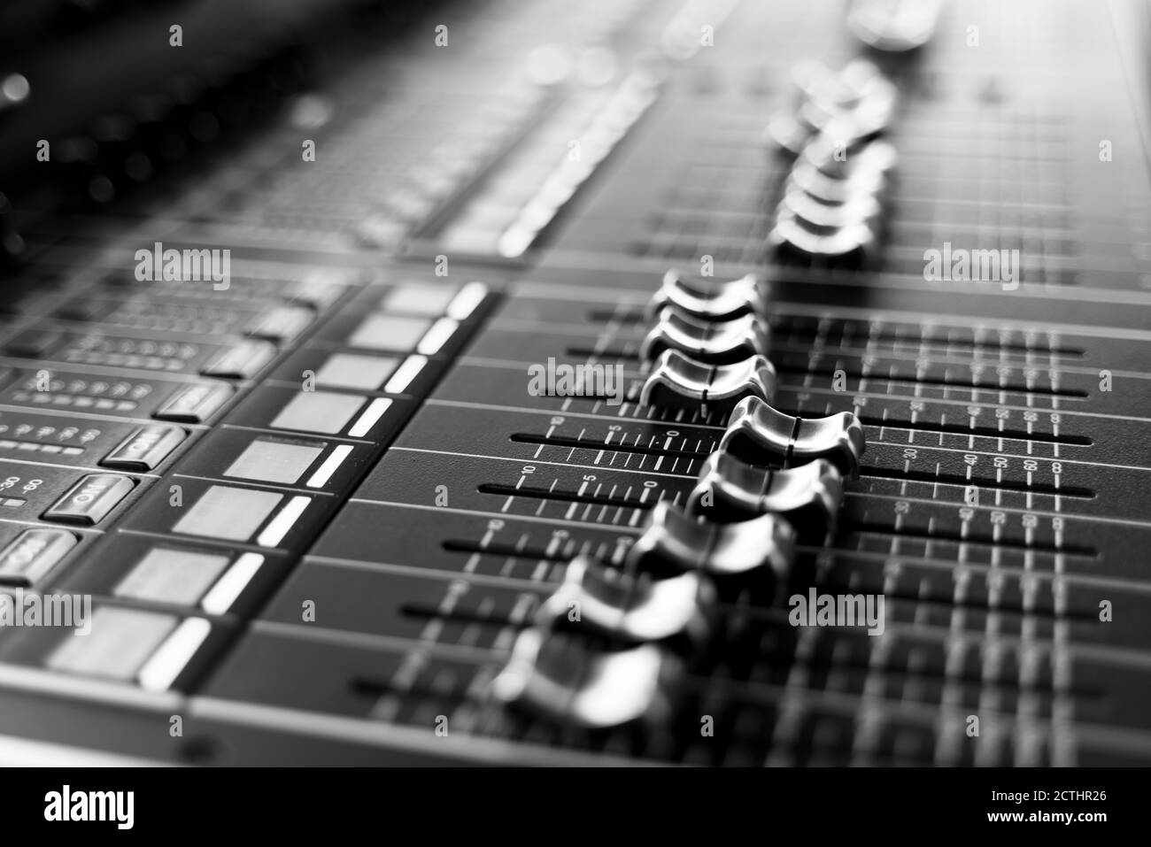 Console professionale di mixaggio audio con fader e manopole di regolazione, messa a fuoco selettiva in bianco e nero Foto Stock
