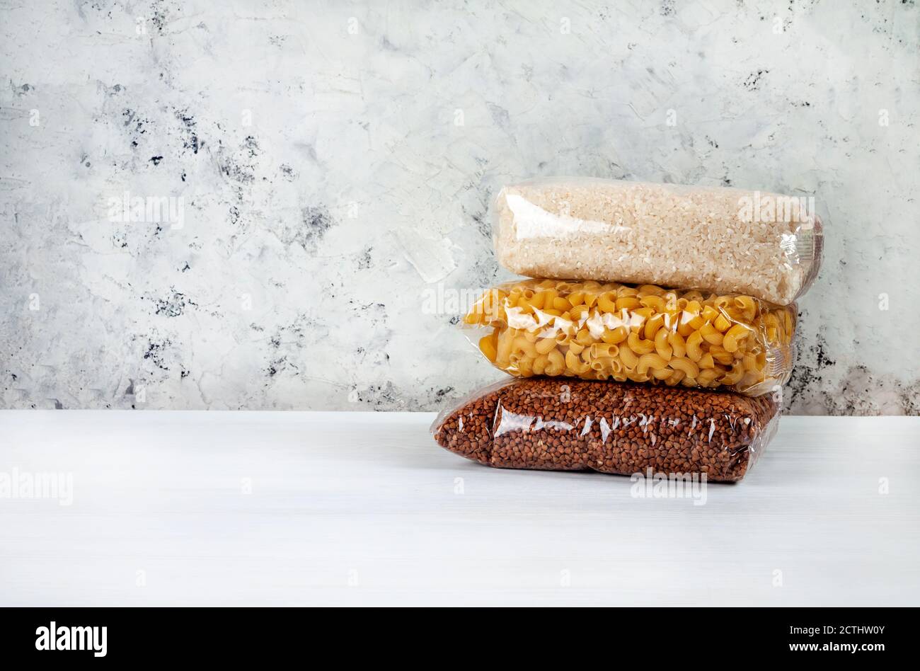 assistenza umanitaria a favore di famiglie povere e grandi. Donazione durante la crisi. Lattine di stagno, cibo in scatola, stufato, grano saraceno, riso, pasta in sacchetti trasparenti Foto Stock