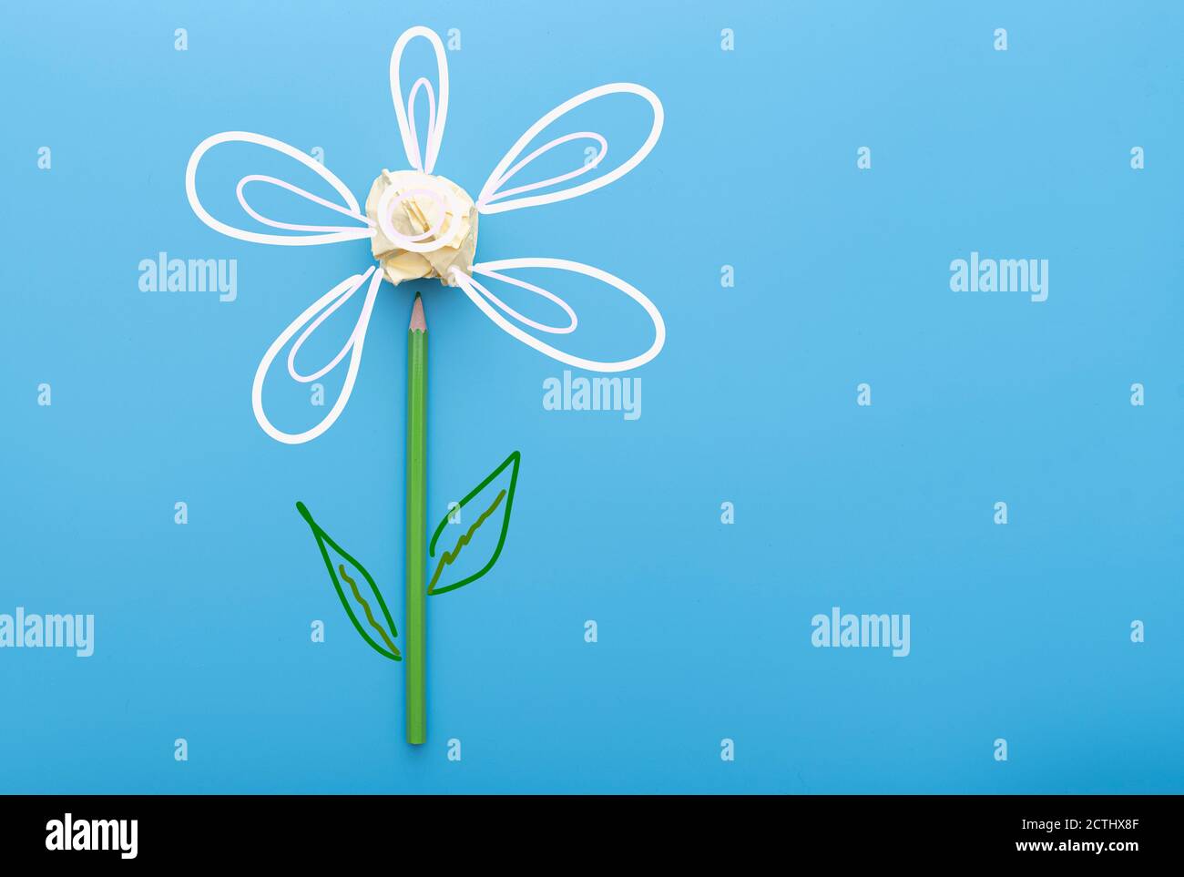 Immagine creativa fiore a matita e sminuzzato su superficie blu Foto Stock