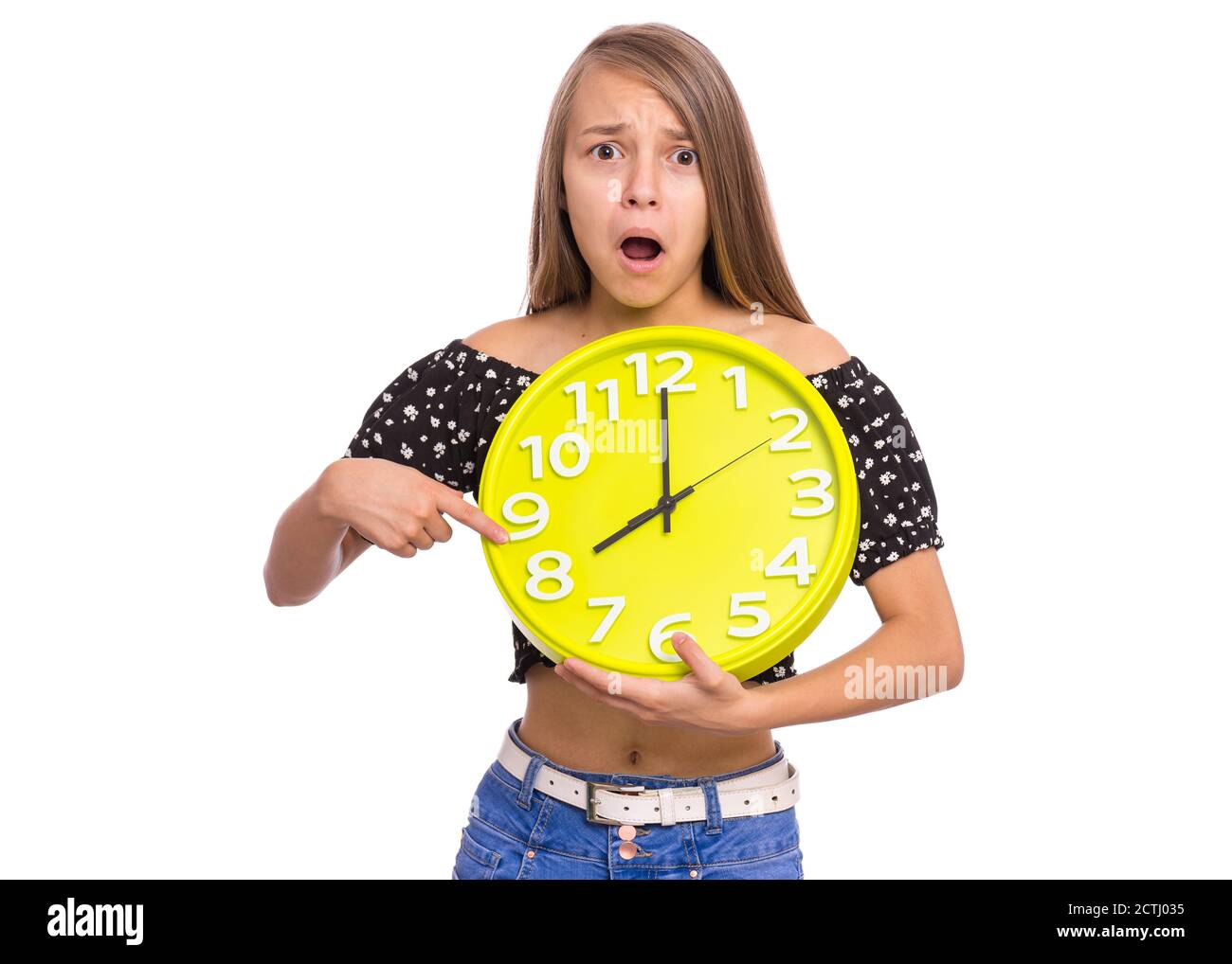Sorpresa ragazza teen tenendo Big clock, isolato su sfondo bianco. Ritratto di adolescente che mostra grande orologio con stress. Scioccato bambino di nuovo a scuola. Foto Stock