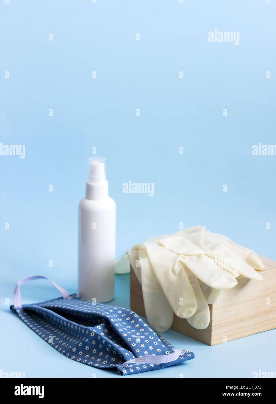 Maschera per dispositivi di protezione individuale, guanti e disinfettante su sfondo blu. Foto Stock