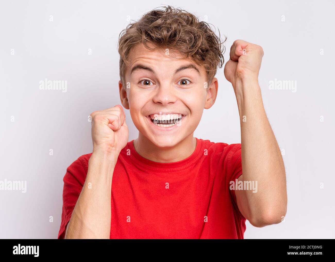 Ritratto di teen boy felice ed eccitato esprimendo gesto vincente. Successo e celebrazione della vittoria, bambino trionfante su sfondo grigio. Foto Stock