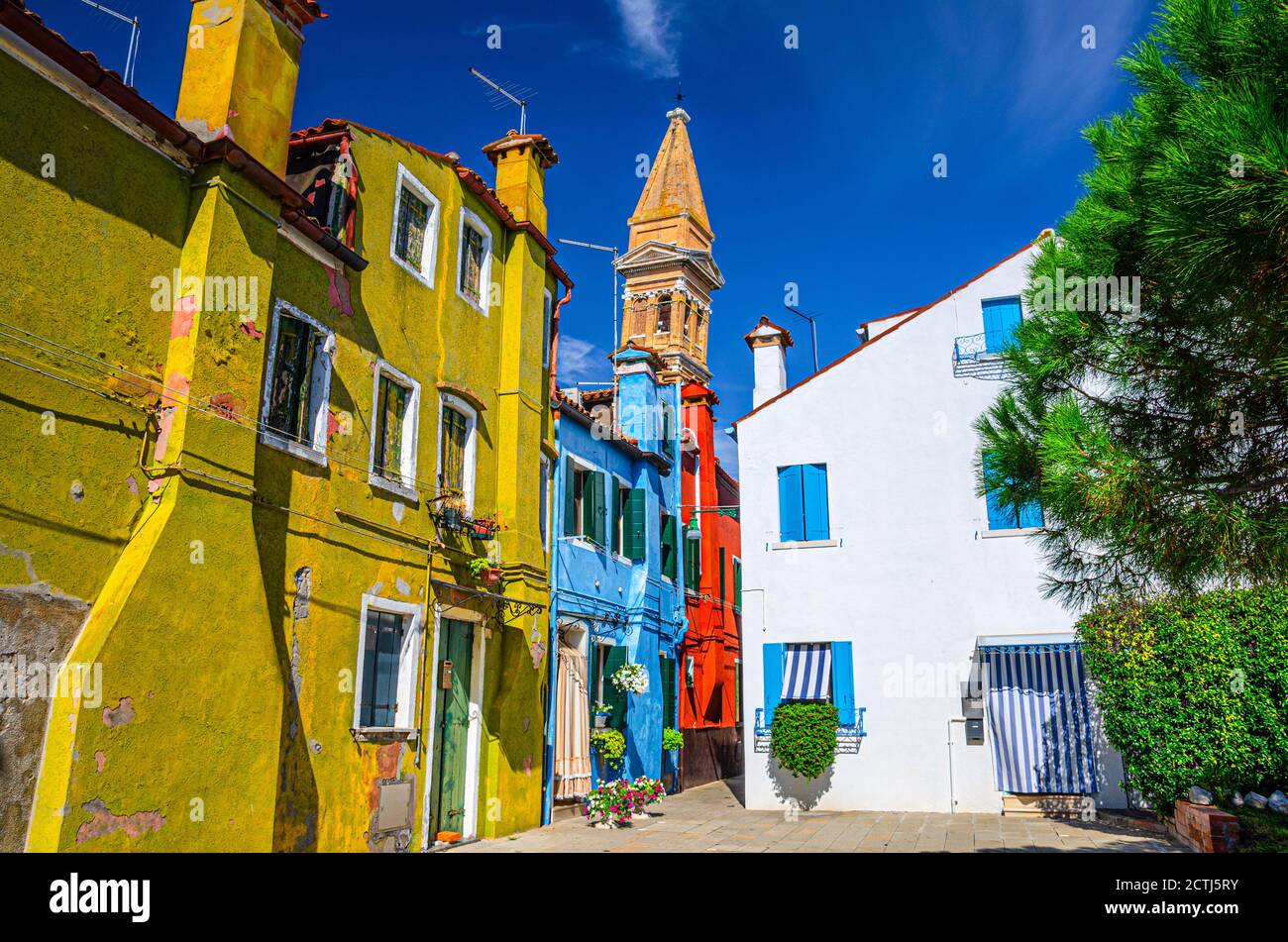 Case colorate con mura multicolore in via dell'isola di Burano, Campanile della chiesa di San Martino e cielo azzurro in piena di sole giornate estive, provincia di Venezia, Regione Veneto, Italia settentrionale. Burano cartolina Foto Stock