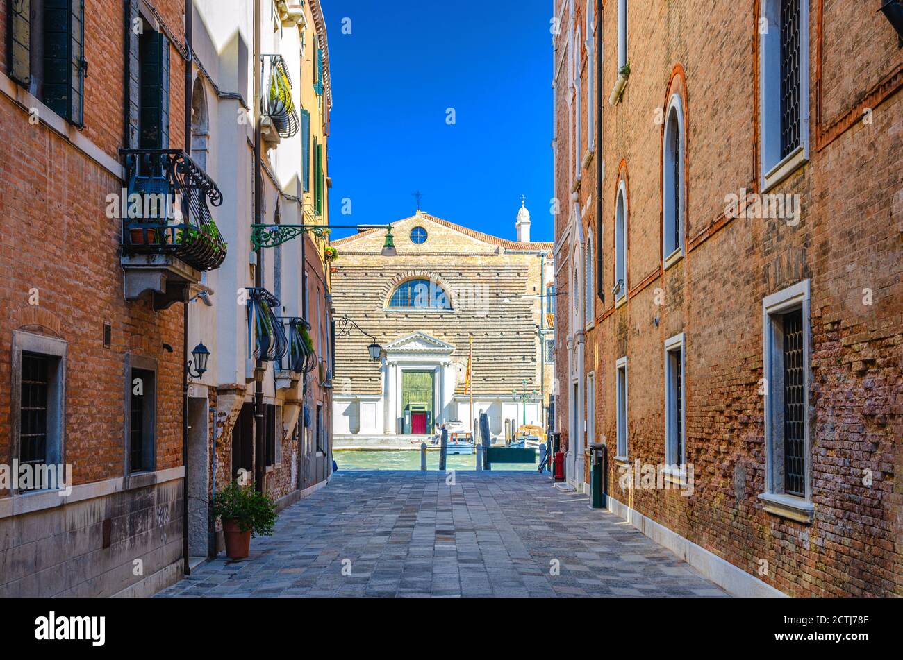 Venezia, Italia, 13 settembre 2019: Strada stretta tra vecchi edifici che conduce al canale Grande nel centro storico della città, chiesa di San Marcuola e cielo blu di fondo in estate Foto Stock