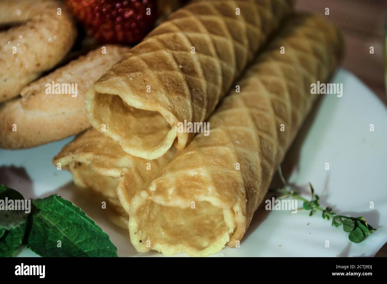 Cialda e biscotti su un piatto bianco e una tazza di tè. Waffle sul lato. Composizione su sfondo di legno. Struttura visibile dei waffle Foto Stock