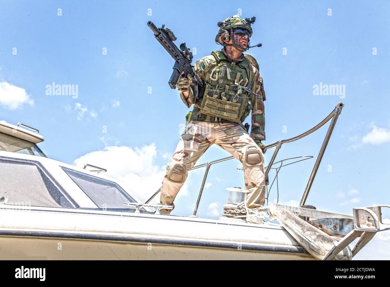 Esercito soldati forze speciali, comandante combattente in munizioni complete, indossare corazza e casco, fucile di servizio armato, in piedi su arco di motoscafo, guardando in lontananza durante il pattugliamento di mare Foto Stock