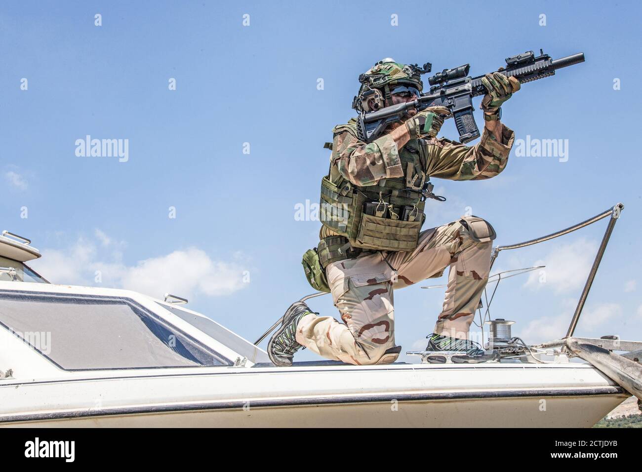 Esercito soldati forze speciali, comandante combattente in munizioni complete, indossare corazza e casco, fucile di servizio armato, in piedi su arco di motoscafo, guardando in lontananza durante il pattugliamento di mare Foto Stock