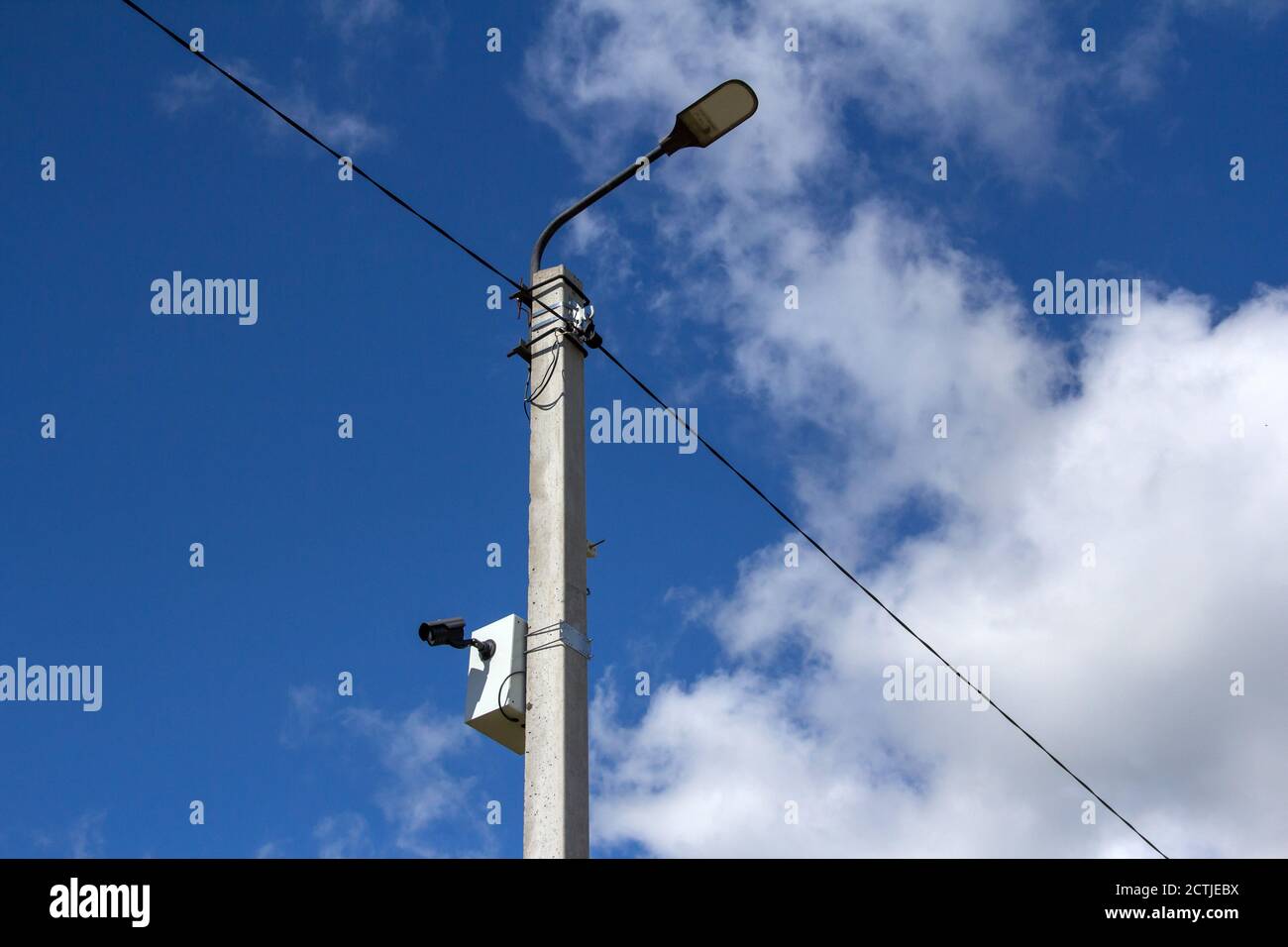 La luce stradale a LED è fiancheggiata da un bellissimo cielo blu sullo sfondo con una videocamera montata su un palo. Sistema di videosorveglianza. Foto Stock