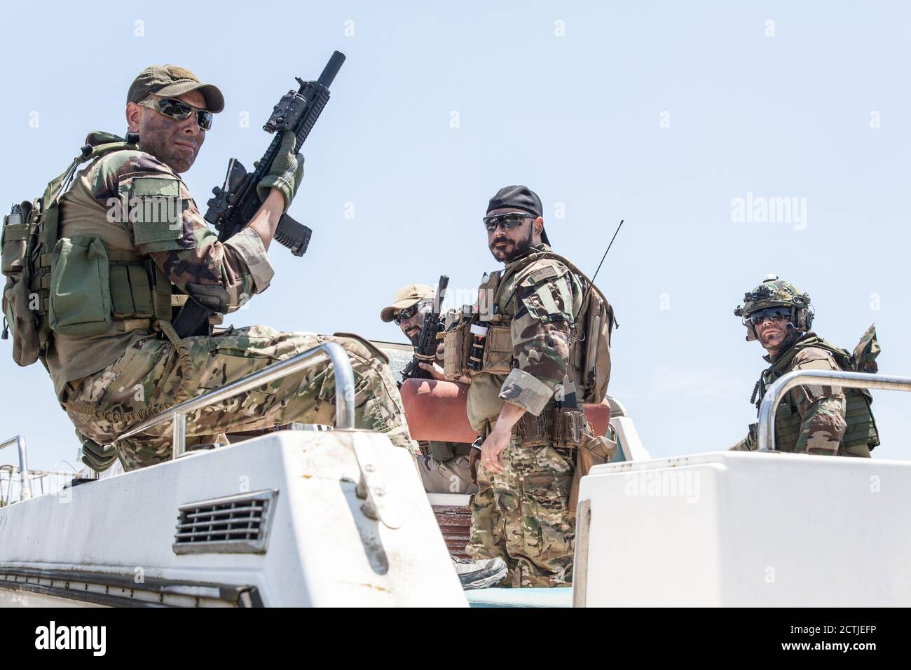 Esercito operazioni speciali soldati, squadra di sigilli, gruppo di combattenti del commando d'elite caricato con munizioni, indossando caschi e cuffie radio, fucili d'assalto armati, in piedi insieme su poppa barca di velocità Foto Stock