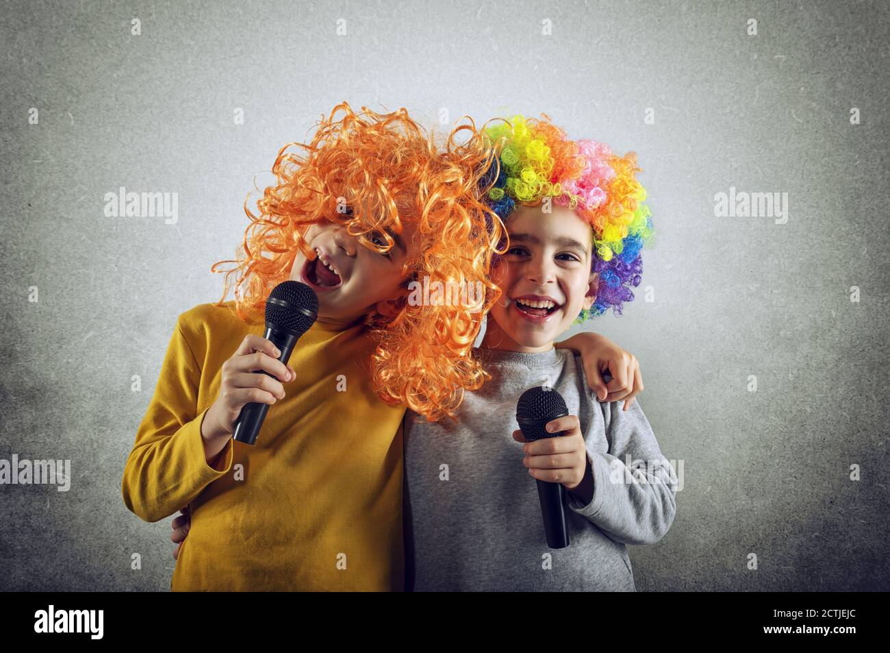 Due bambini cantano una canzone con microfono e wig divertente Foto Stock