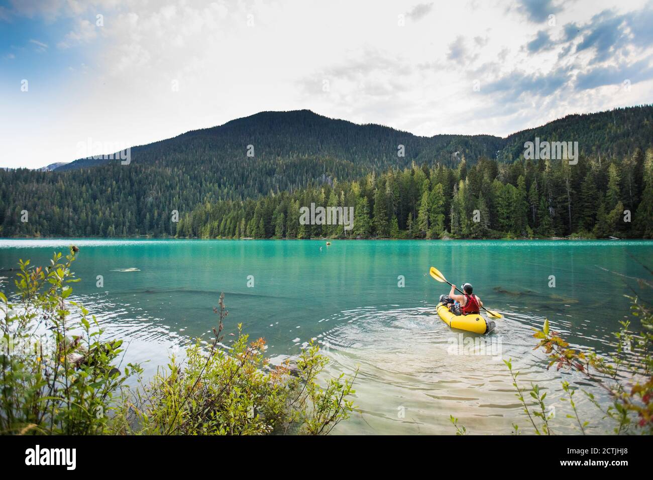 Uomo che paddling packraft gonfiabile sul lago di Cheakamus, Whistler, B.C. Foto Stock