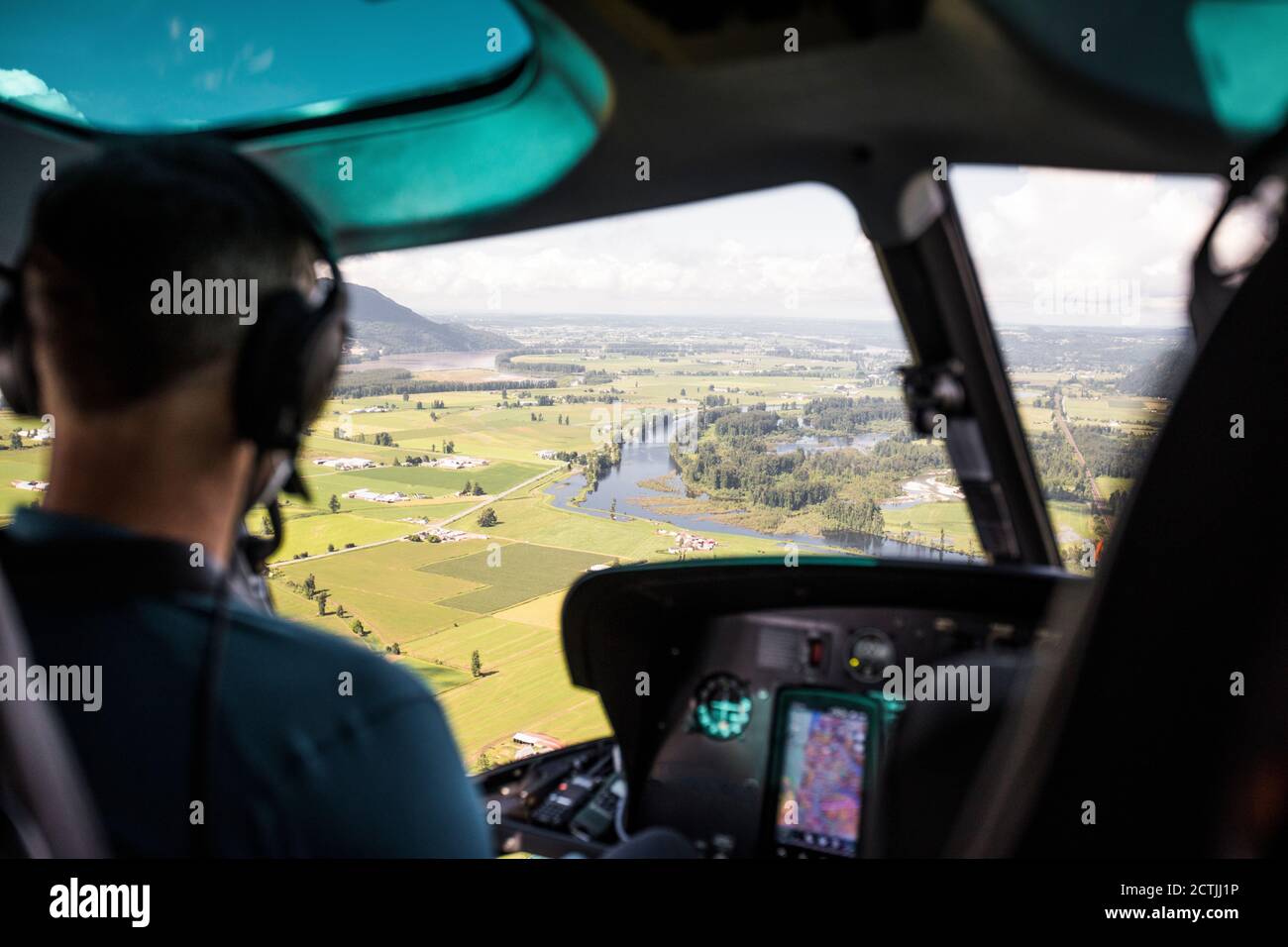 Pilota in elicottero che guarda verso i terreni agricoli della Fraser Valley. Foto Stock