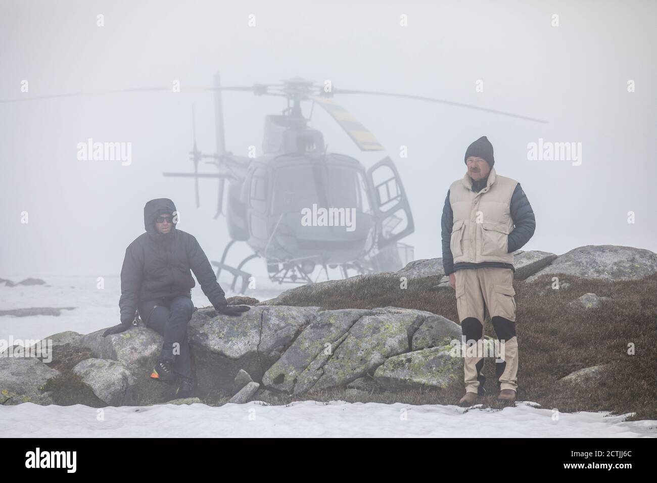 Il pilota dell'elicottero e il passeggero aspettano sulla montagna per fare in modo che le condizioni meteorologiche si chiarano. Foto Stock