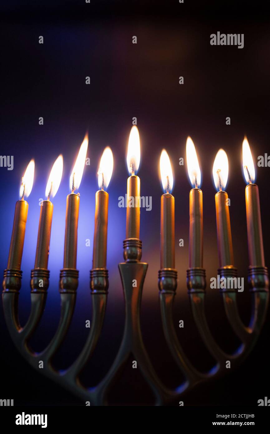 Hanukah candele accese in Menorah contro sfondo colorato Foto Stock