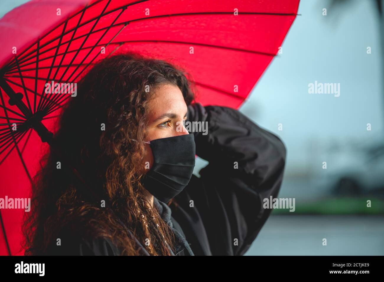Ritratto di una donna riccia che tiene un ombrello rosso a Palma, Spagna Foto Stock