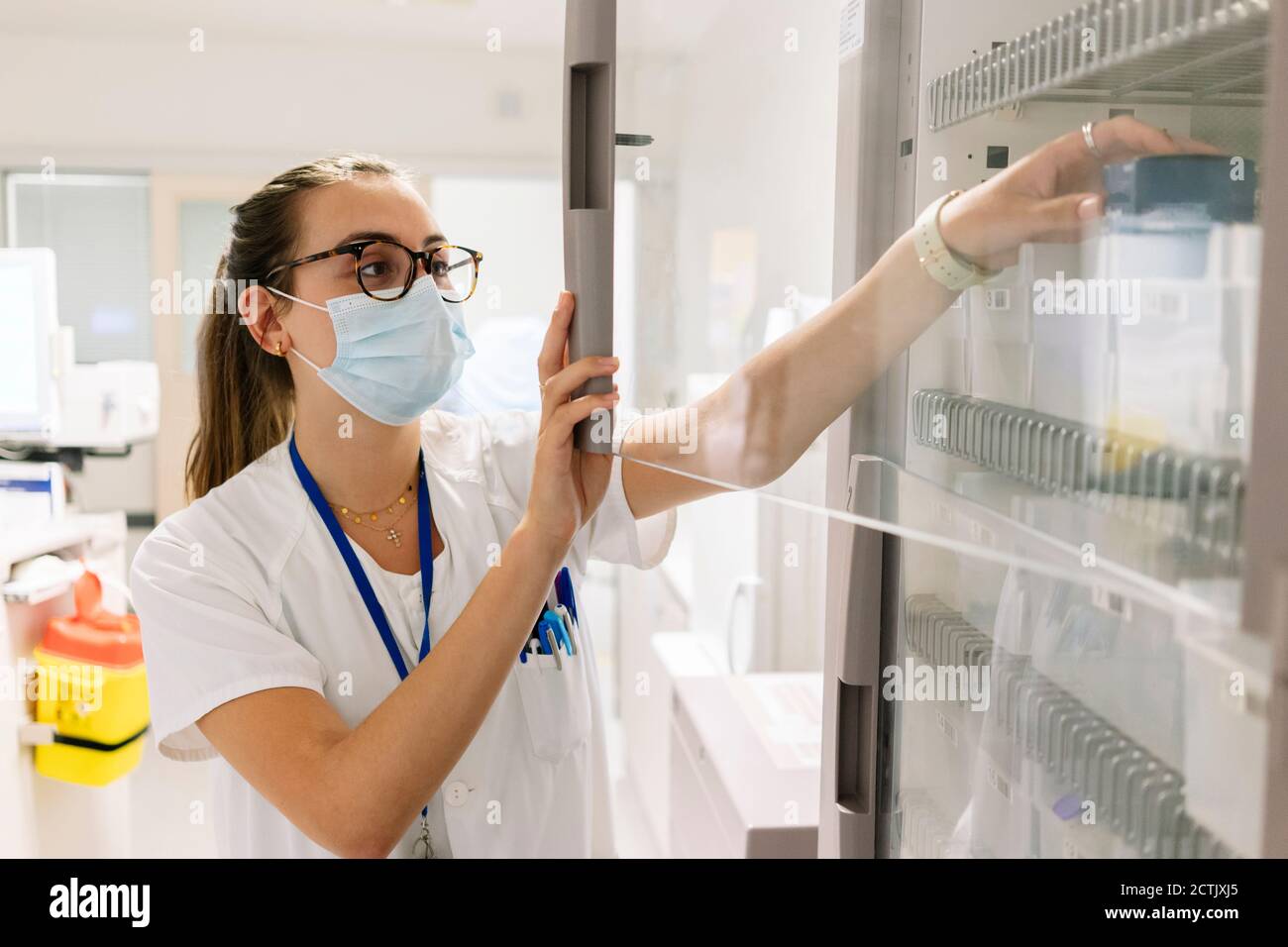 Medico femminile che prende i medicinali dal gabinetto in farmacia all'ospedale Foto Stock