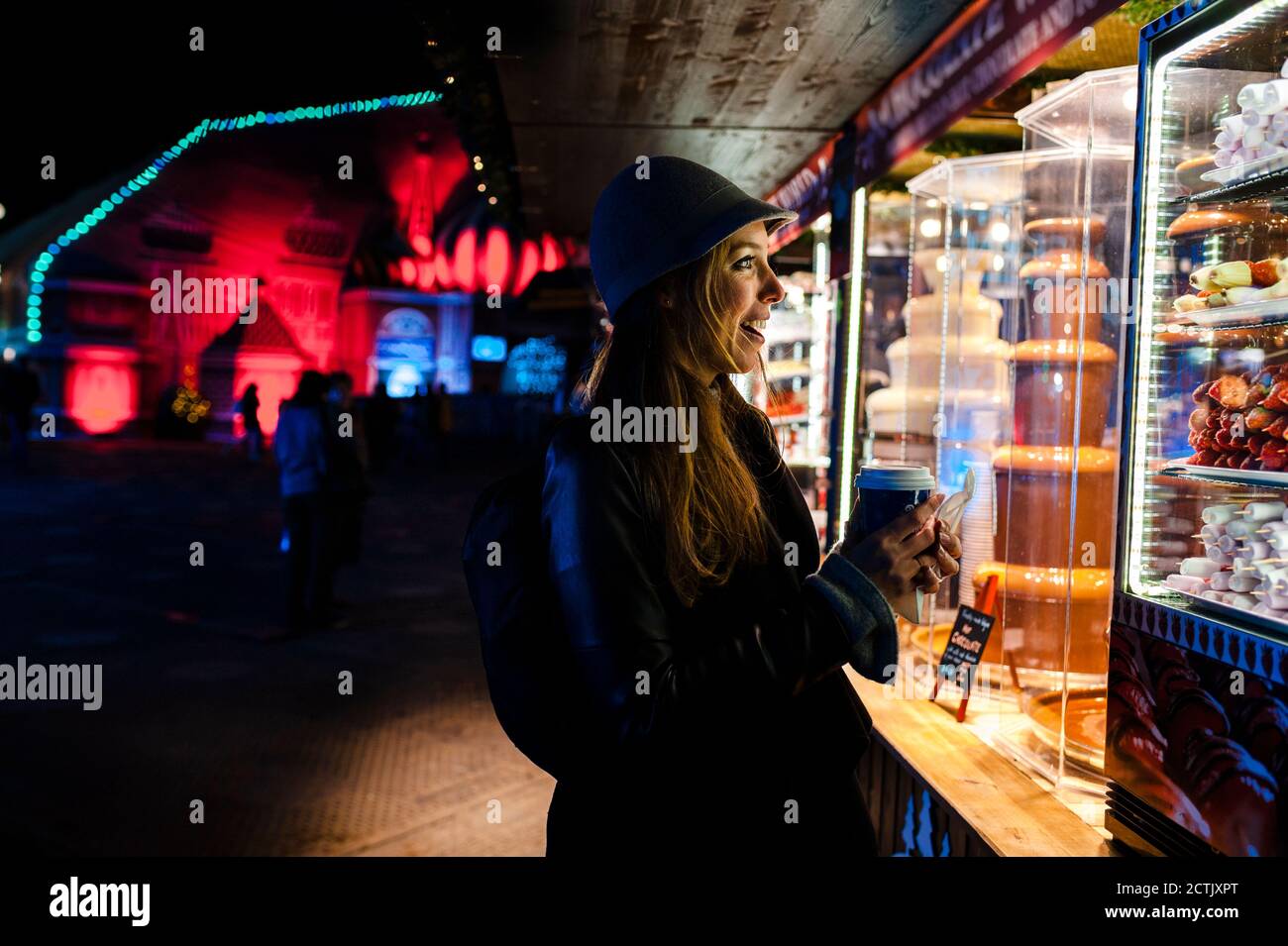 Donna sorridente che guarda un stand sul terreno da fiera di notte Foto Stock