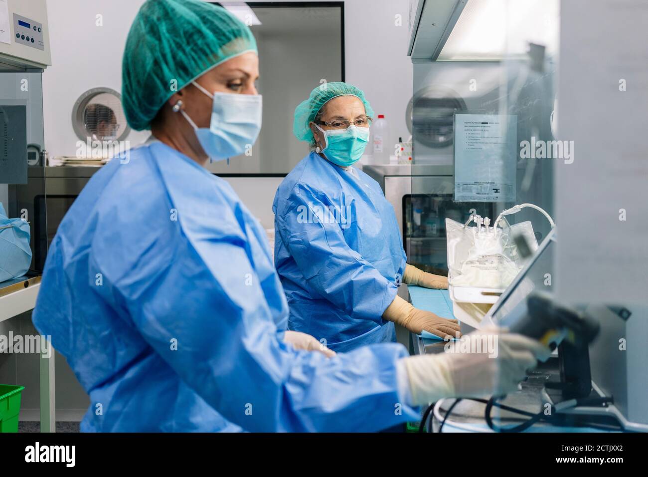 Farmacista che guarda una collega femmina che tiene in mano lo scanner per codici a barre laboratorio Foto Stock