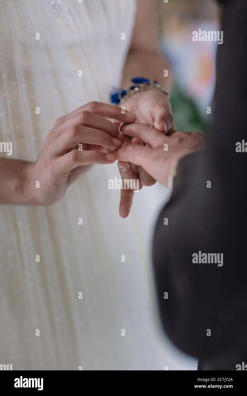 Sposa che mette l'anello di nozze nel dito dello sposo Foto Stock