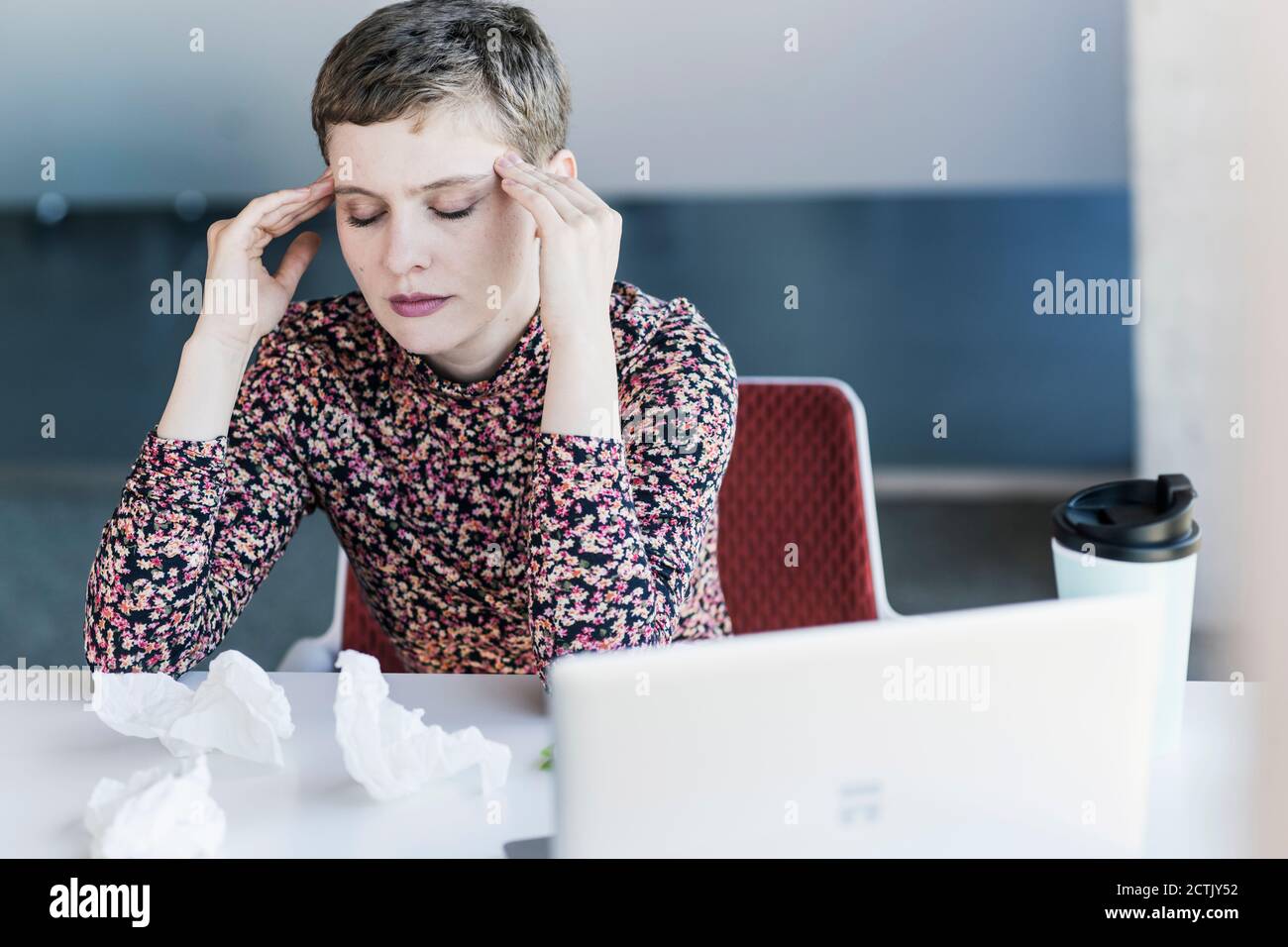 Donna d'affari alla scrivania in ufficio che ha mal di testa Foto Stock