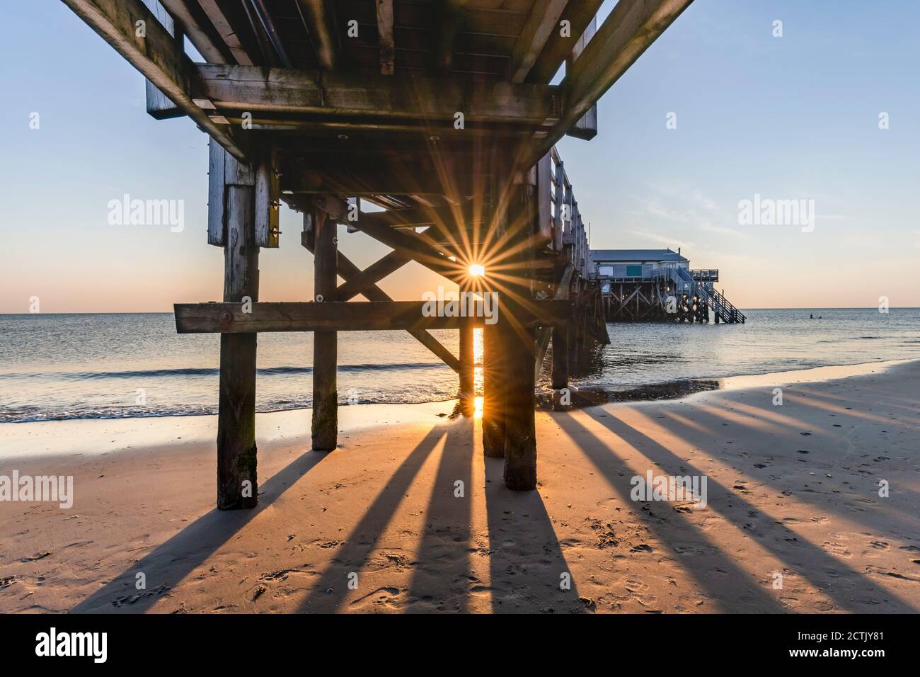 Germania, Schleswig-Holstein, Sankt Peter-Ording, sotto il molo costiero al tramonto Foto Stock