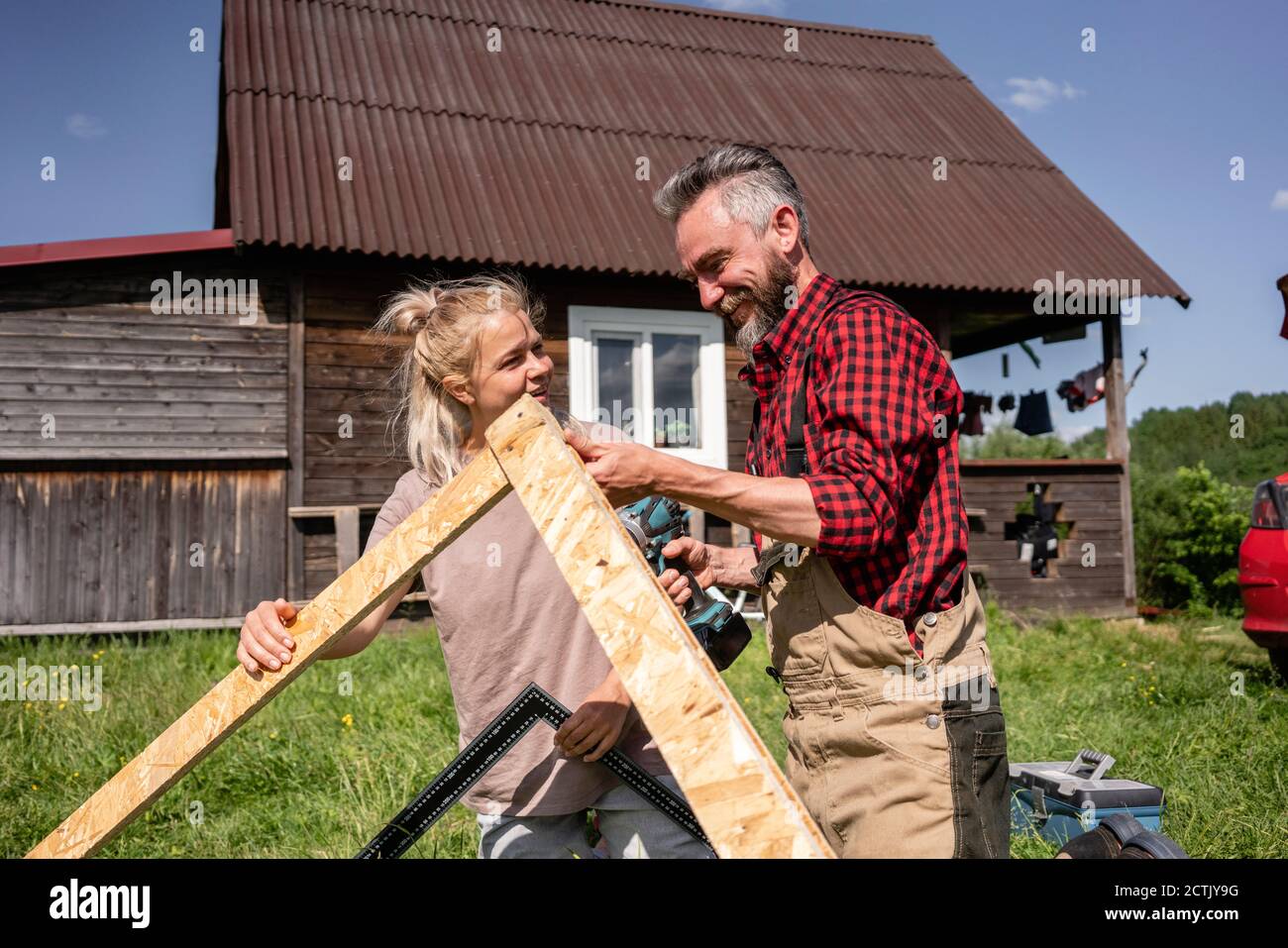 Falegname e donna che lavorano insieme per fare casa per i bambini il giorno di sole Foto Stock