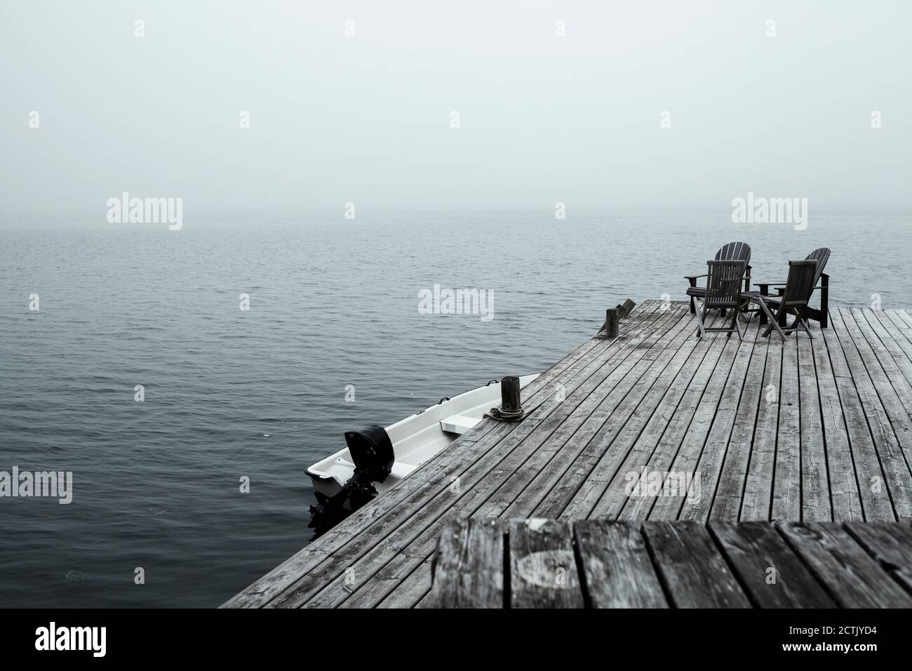Sedie a sdraio vuote sul molo costiero all'alba foggy Foto Stock