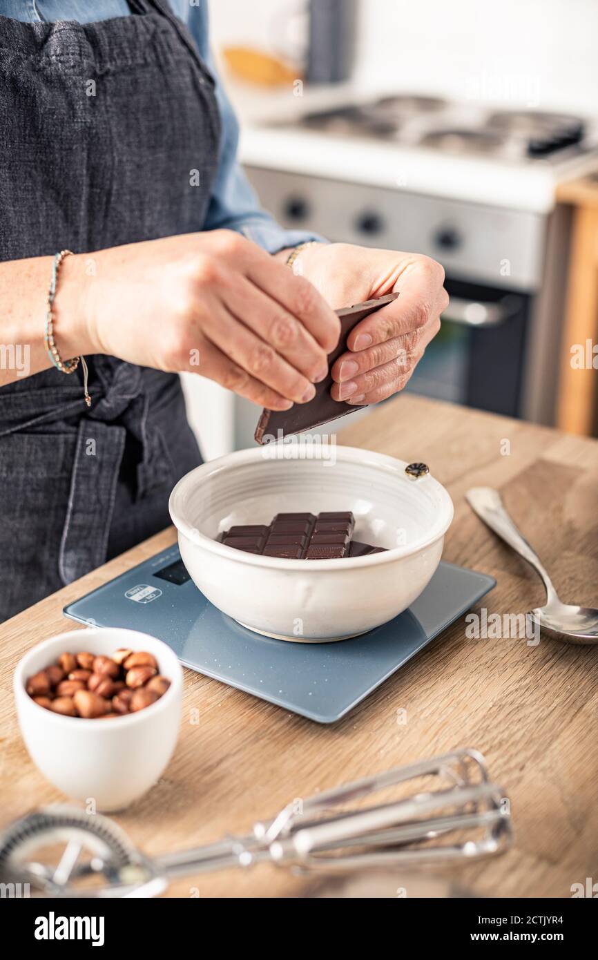 Donna che pesa la barretta di cioccolato mentre sta in piedi la cucina a casa Foto Stock