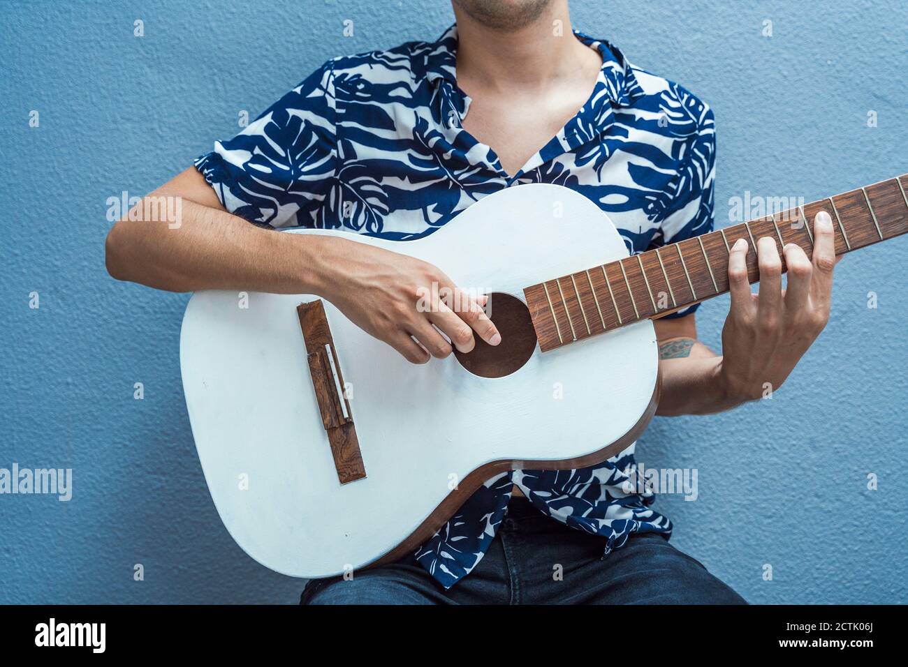 Musicista che suona la chitarra contro la parete blu Foto Stock