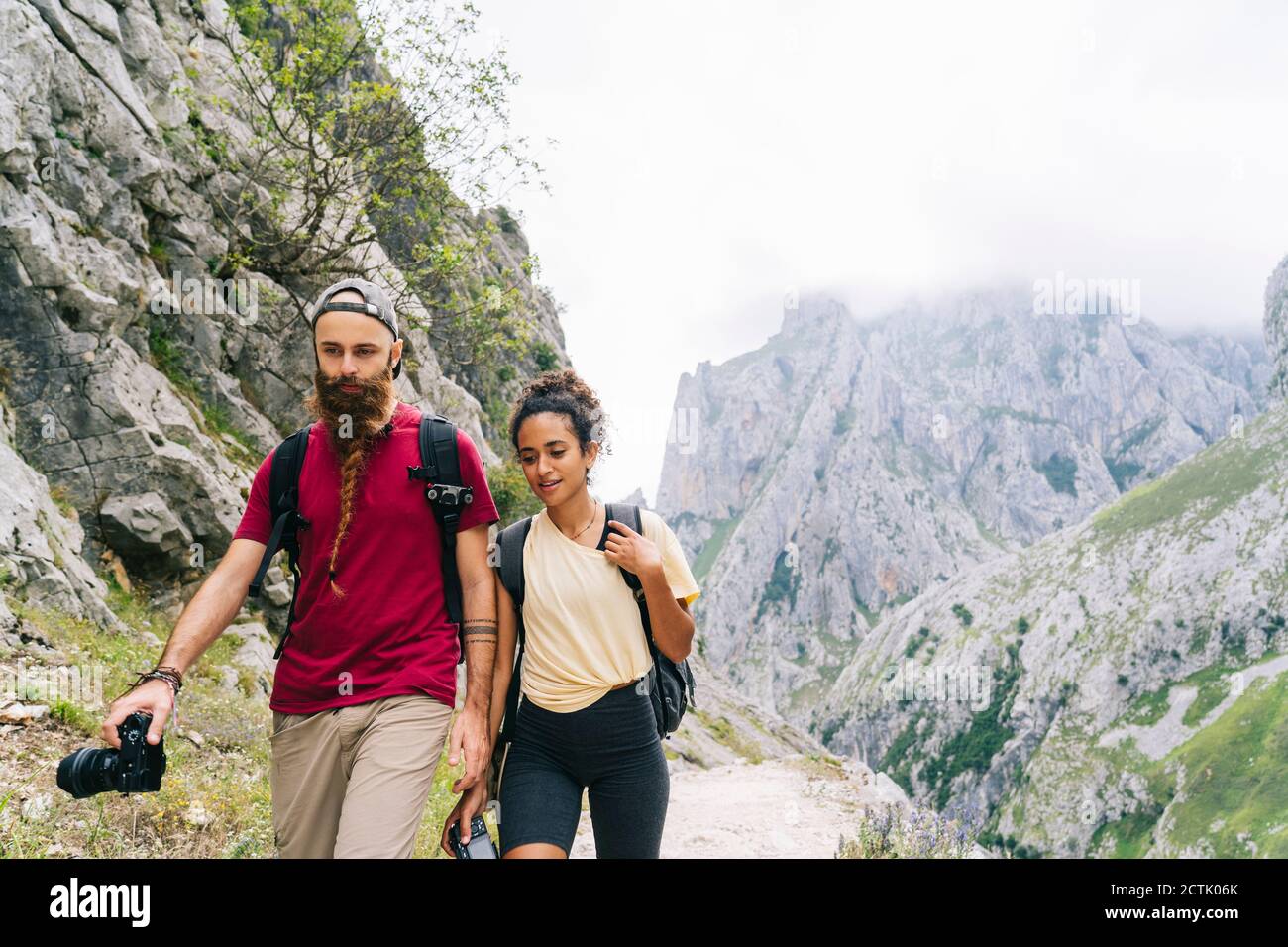 Escursionista che tiene la fotocamera durante le escursioni sul sentiero di montagna a Ruta del Cares, Asturias, Spagna Foto Stock