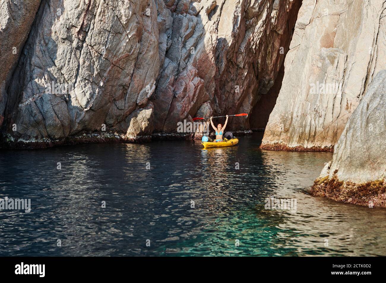 Donna kayak mentre si tiene un rombo sopra testa contro la montagna Foto Stock