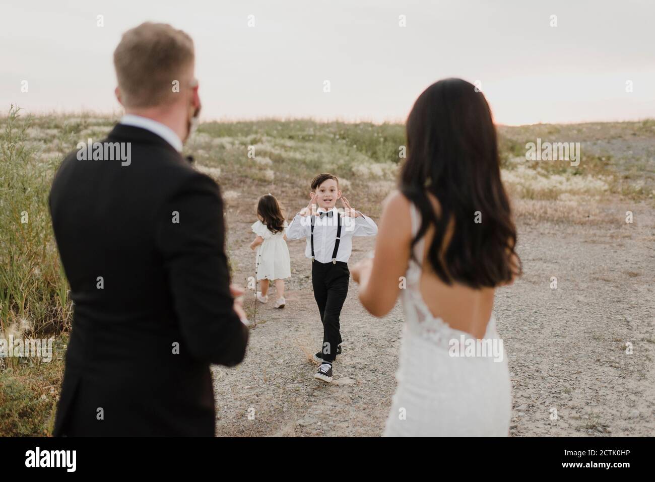 Figlio che parla con i genitori mentre figlia cammina contro il cielo durante COVID-19 Foto Stock