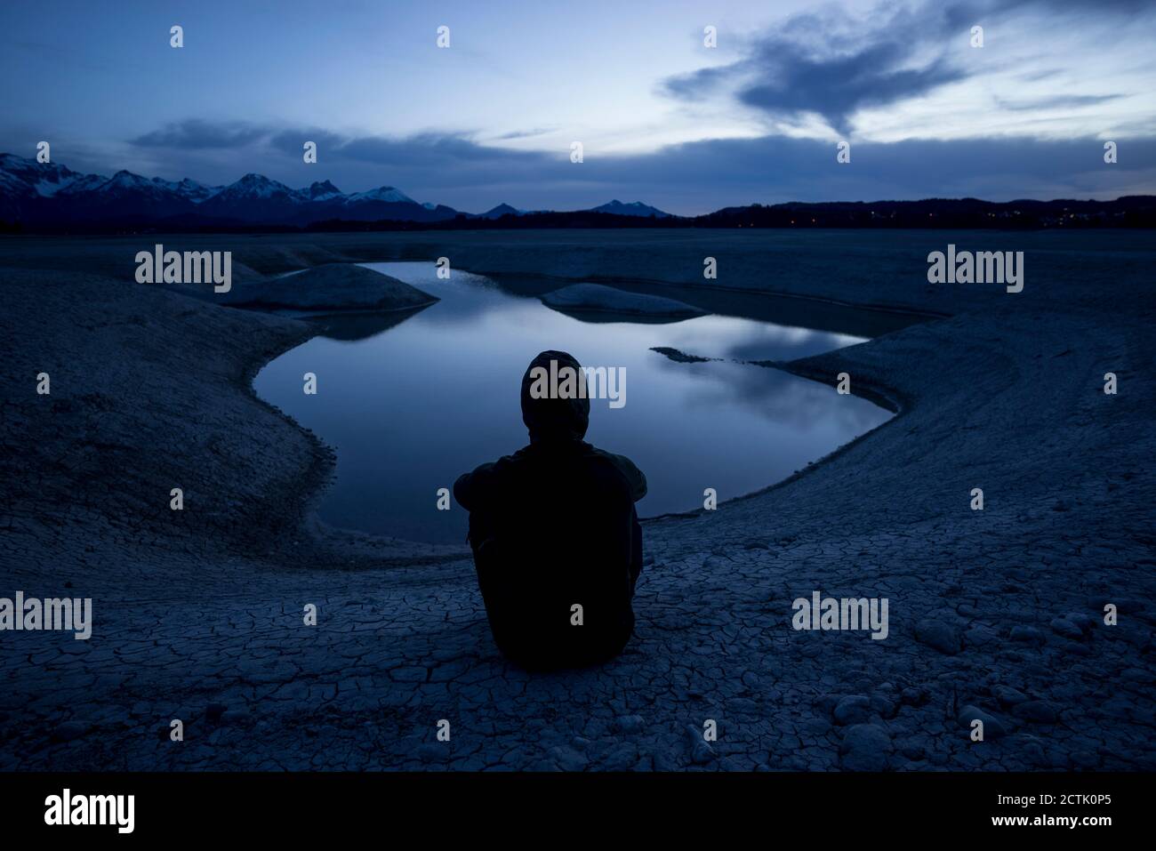 Germania, Baviera, Silhouette di uomo agganciato che ammirano il lago di Forggensee al crepuscolo Foto Stock