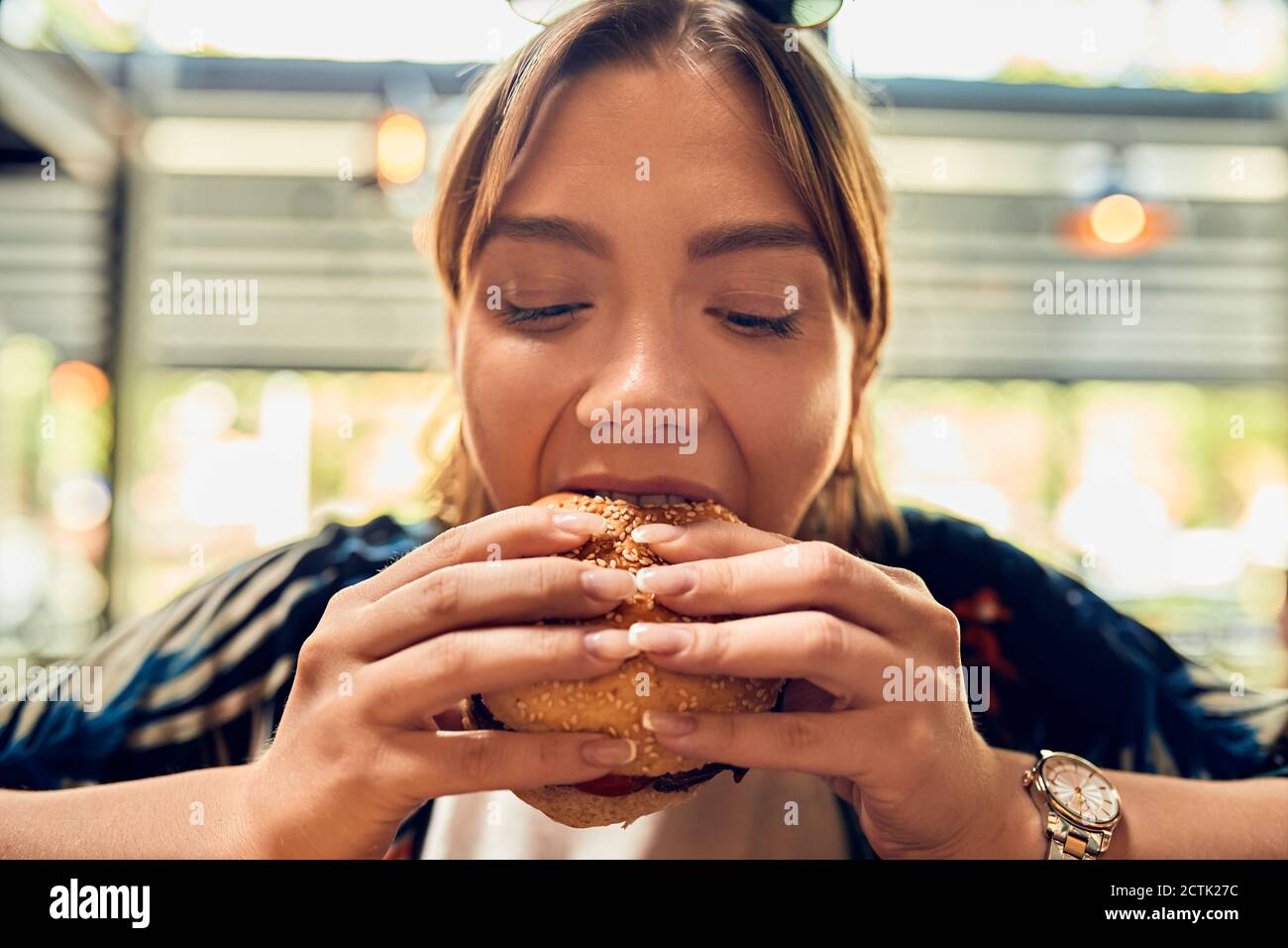 Ritratto di donna che mangia un hamburger Foto Stock