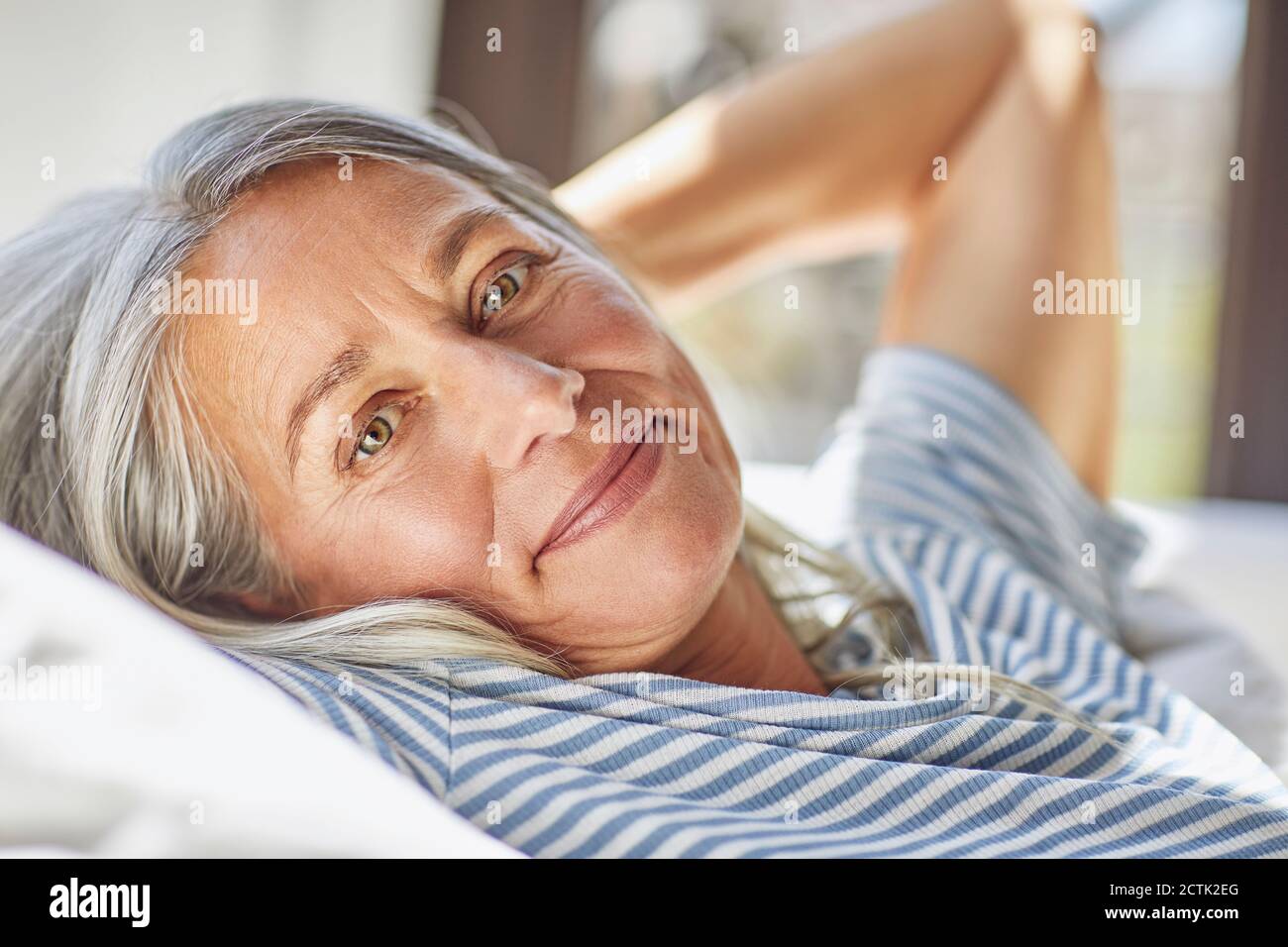 Primo piano di una donna sorridente che si rilassa con le mani dietro la mano soggiorno Foto Stock
