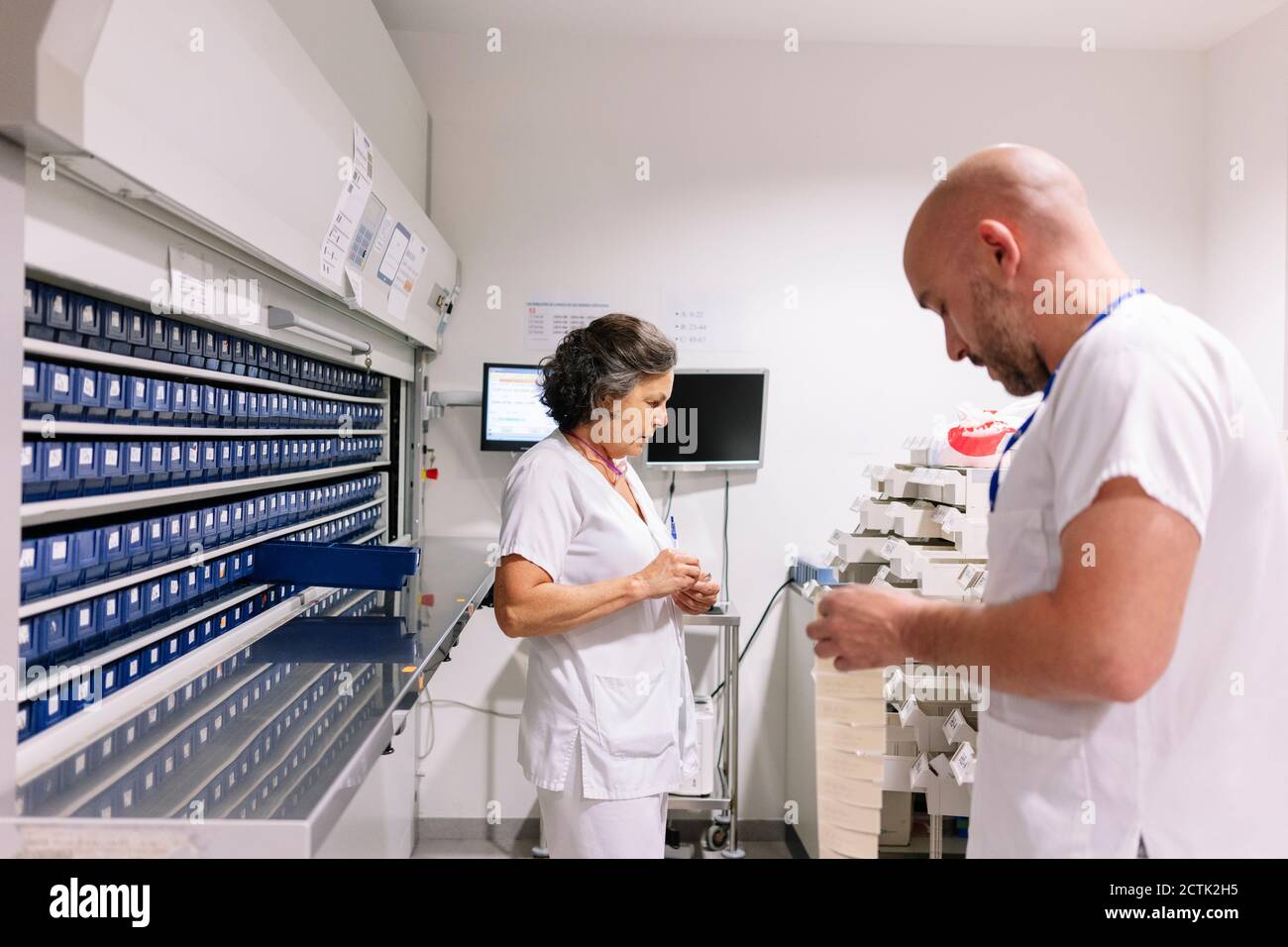 Farmacisti di sesso maschile e femminile che lavorano in sala di stoccaggio in ospedale Foto Stock