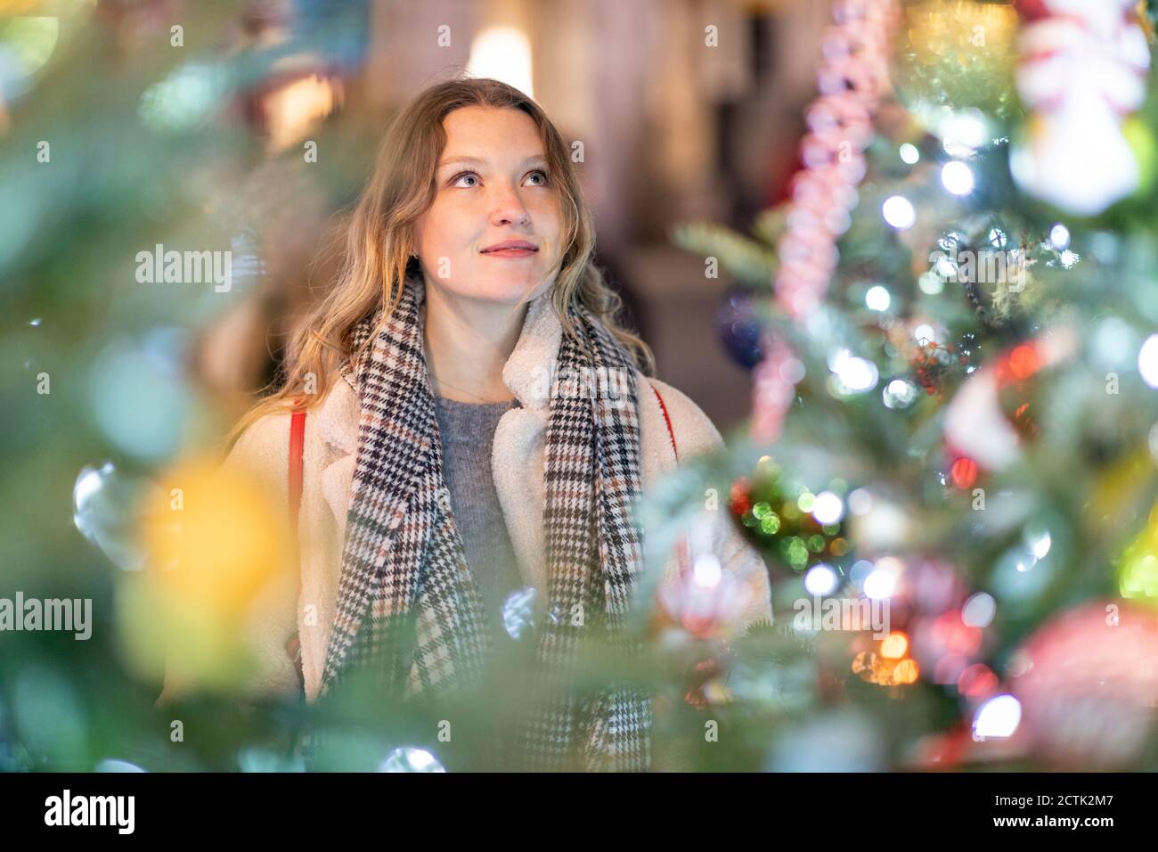 Giovane donna che guarda l'albero di Natale illuminato e le luci dentro città Foto Stock