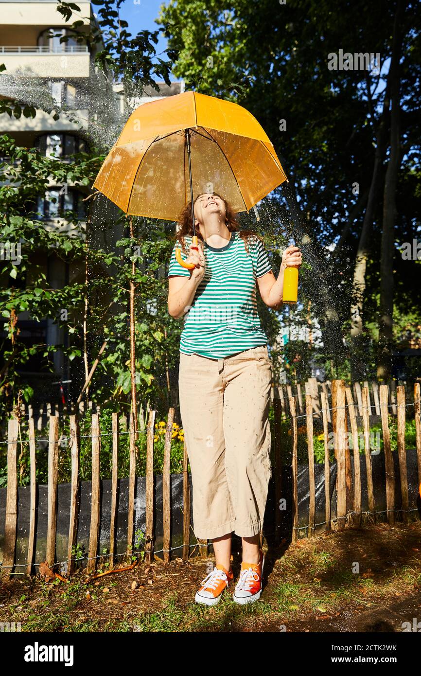 Giovane donna ridente con ombrello e limonata in giardino Foto Stock