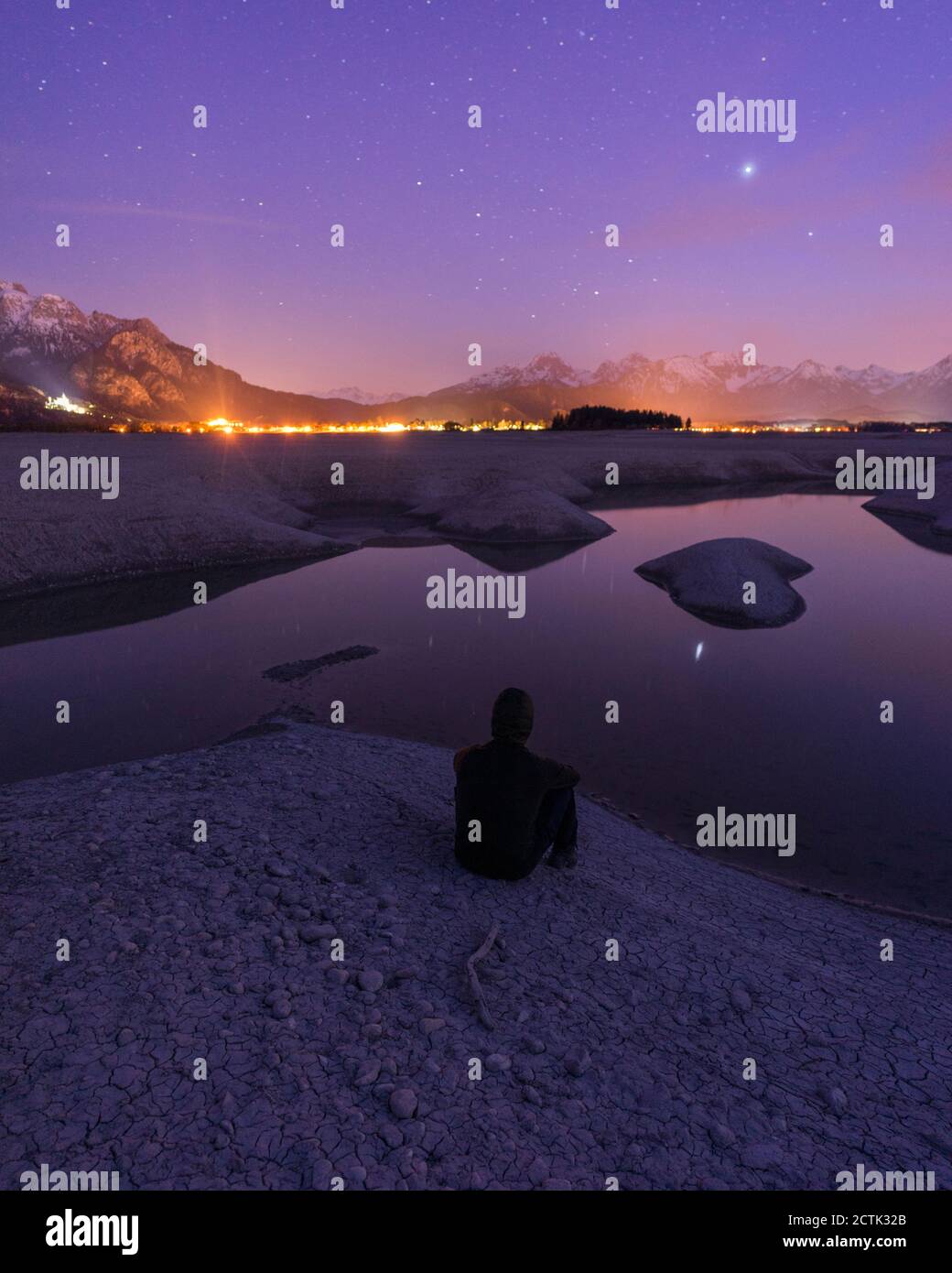 Germania, Baviera, Silhouette di uomo incappucciato ammirando il lago di Forggensee nella notte viola Foto Stock