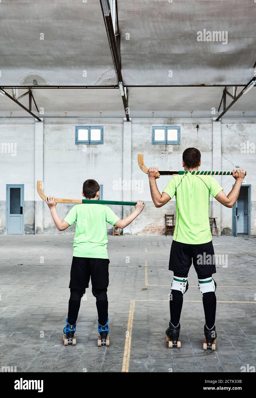 Padre e figlio che tengono i bastoni da hockey al campo sportivo Foto Stock