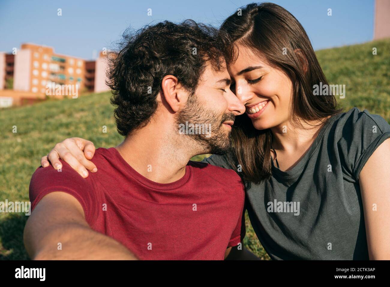 Uomo e donna seduti faccia a faccia sull'erba Foto Stock